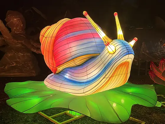 Caracol luminoso LED con la concha en espiral multicolor, sobre una hoja iluminada