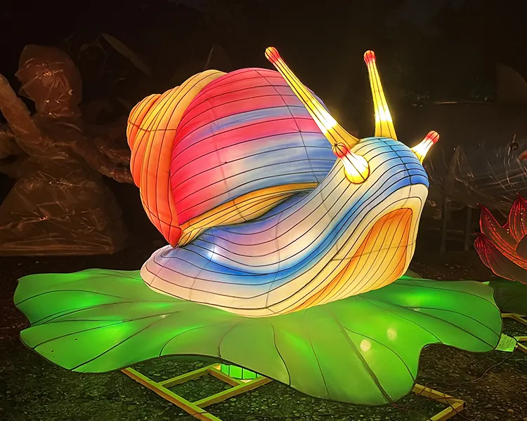 Caracol luminoso LED con la concha en espiral multicolor, sobre una hoja iluminada